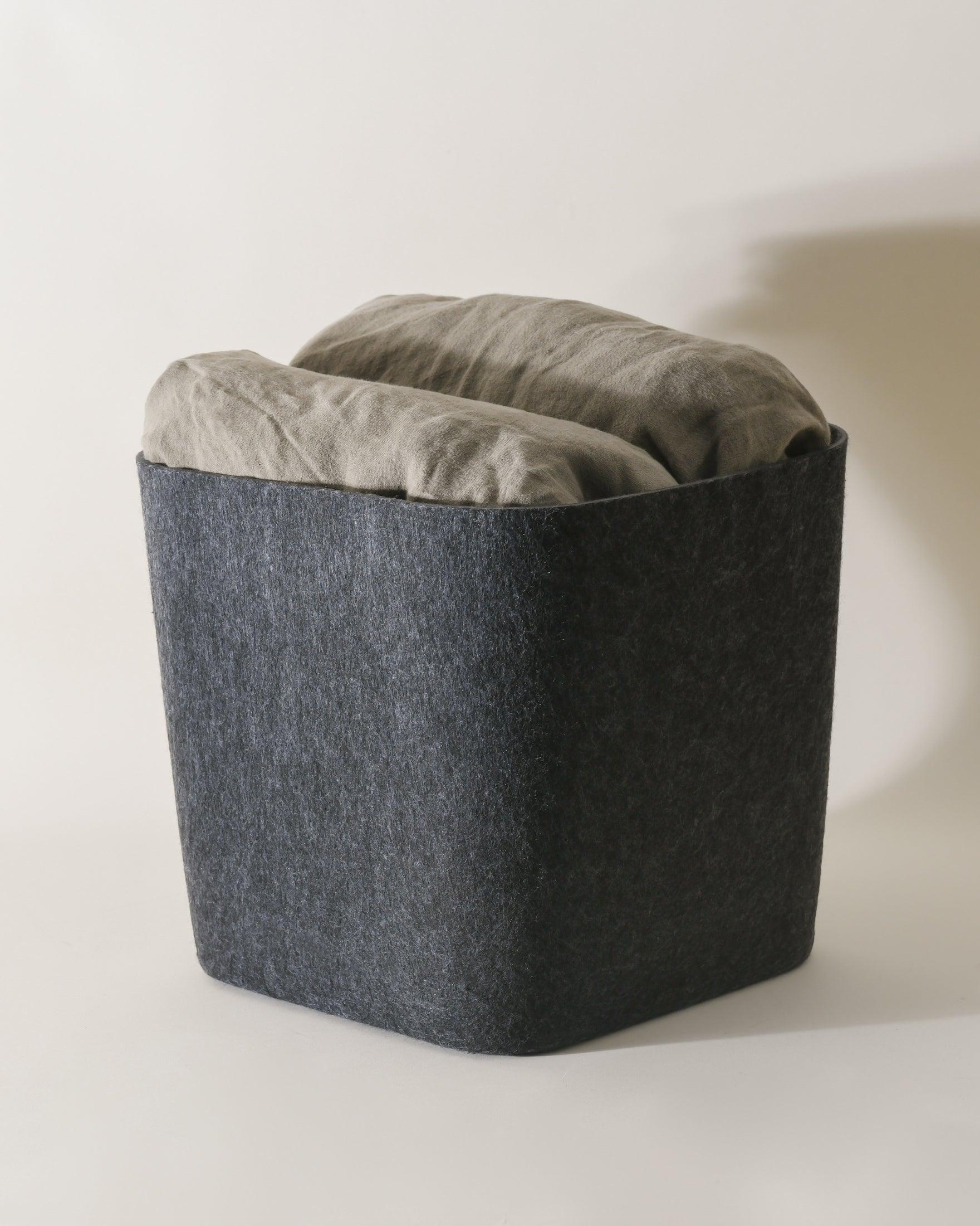 SortJoy Sculpted Storage Bin in Carbon colorway, structured shape on a shelf holding folded linens