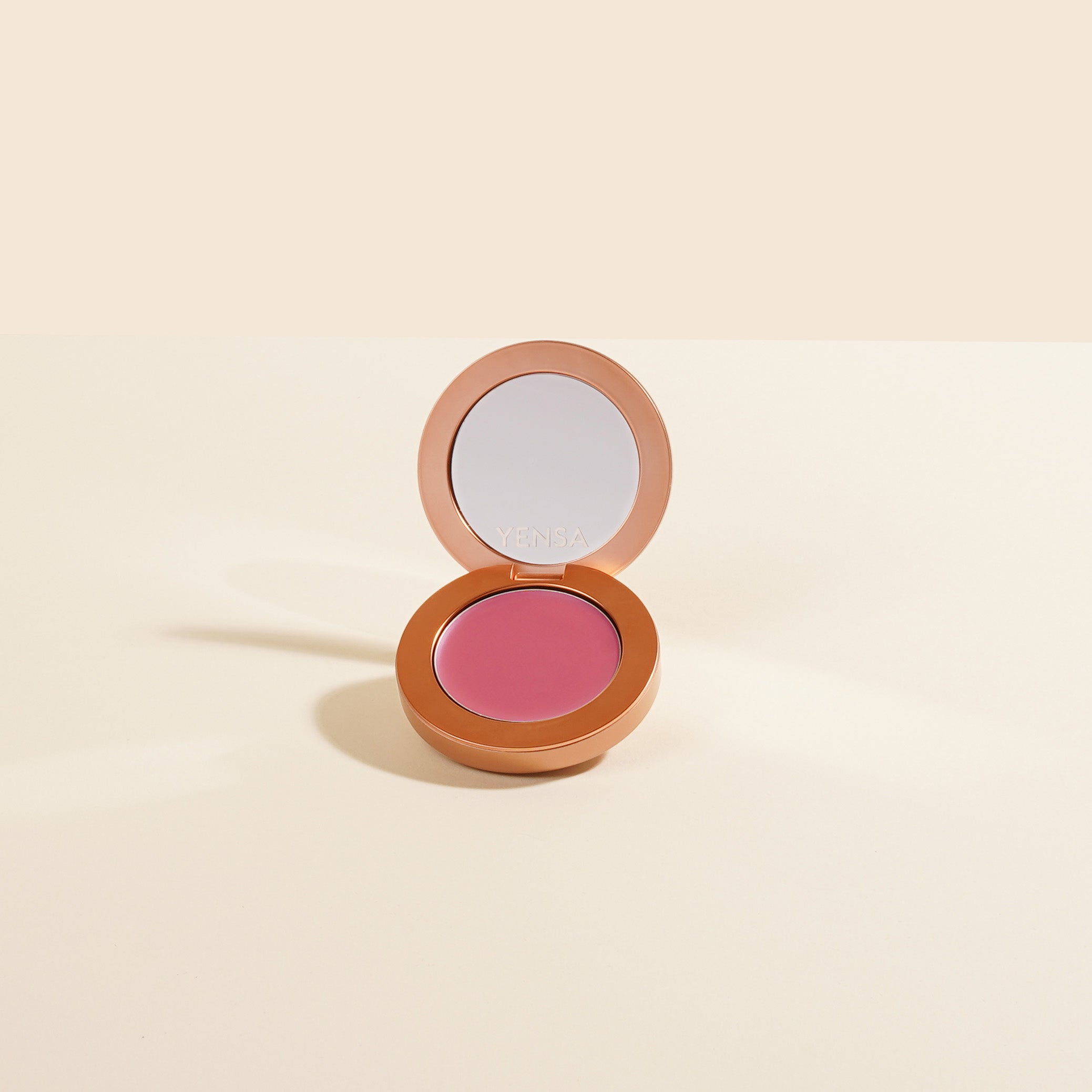 Close-up of buildable cream blush compact with a soft rosy swatch on fair skin showing a dewy, natural flush