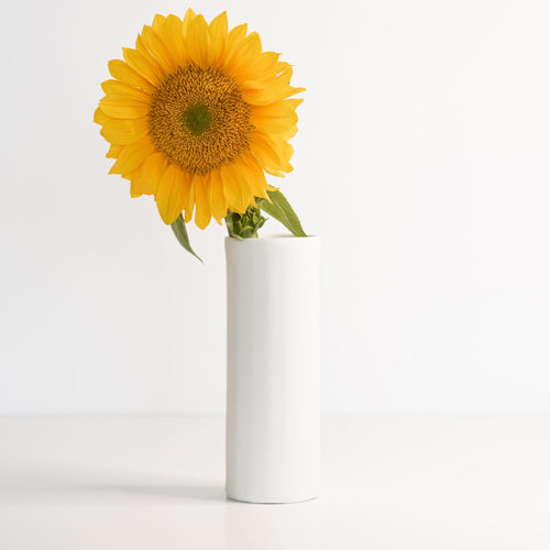 Ember Collective Bloom Vase, handmade white porcelain with a subtle oval rim, 8 inches tall, holding a small floral arrangement