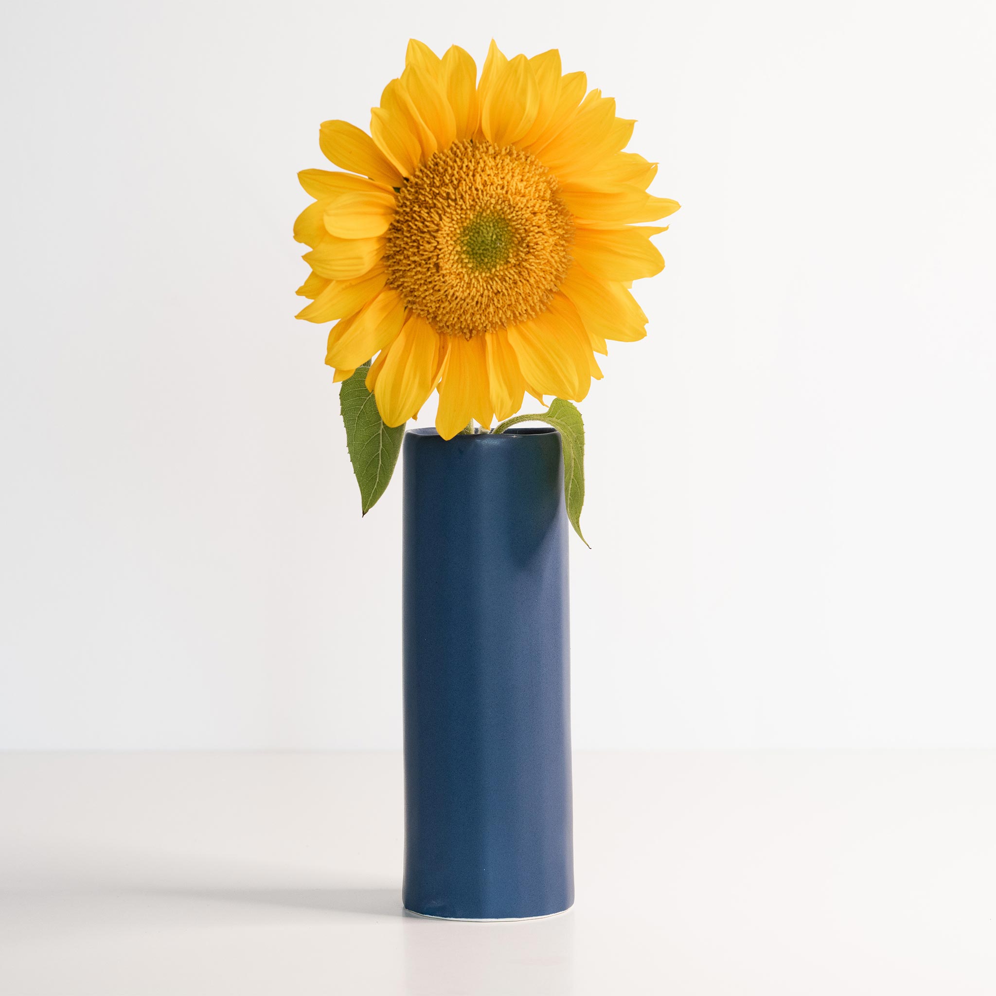 Ember Collective Bloom Vase, handmade white porcelain with a subtle oval rim, 8 inches tall, holding a small floral arrangement