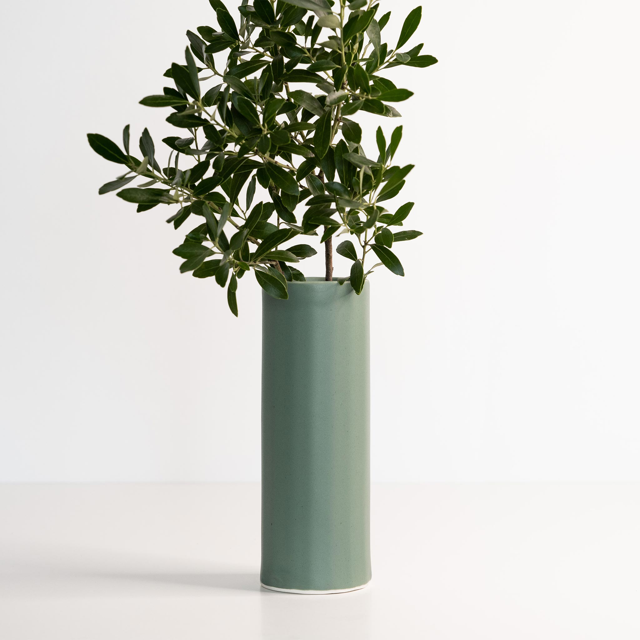 Ember Collective Bloom Vase, handmade white porcelain with a subtle oval rim, 8 inches tall, holding a small floral arrangement
