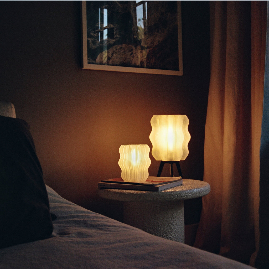 Wavy sculptural table lamp in recycled corn-based plastic with organic rippled silhouette on a flat surface
