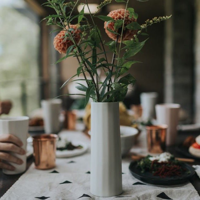 Ember Collective Bloom Vase, handmade white porcelain with a subtle oval rim, 8 inches tall, holding a small floral arrangement