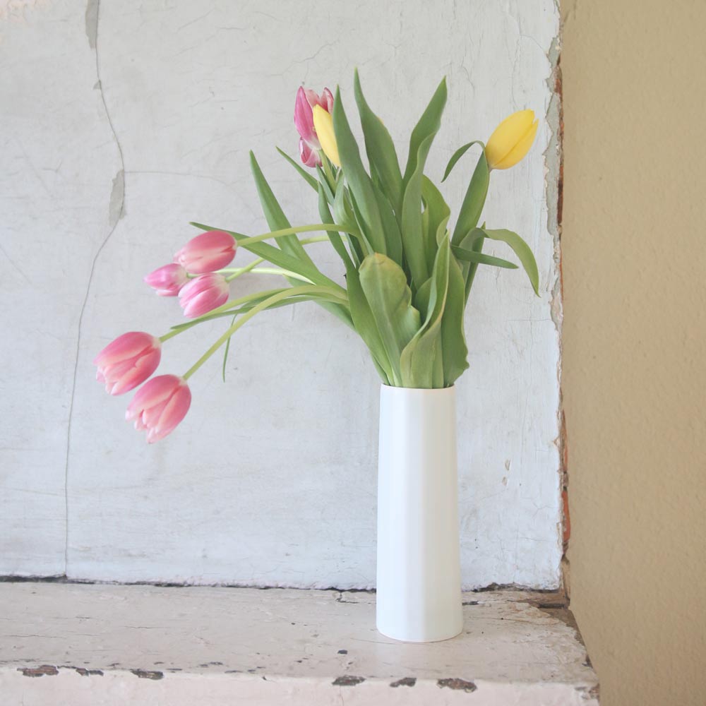 Ember Collective Bloom Vase, handmade white porcelain with a subtle oval rim, 8 inches tall, holding a small floral arrangement