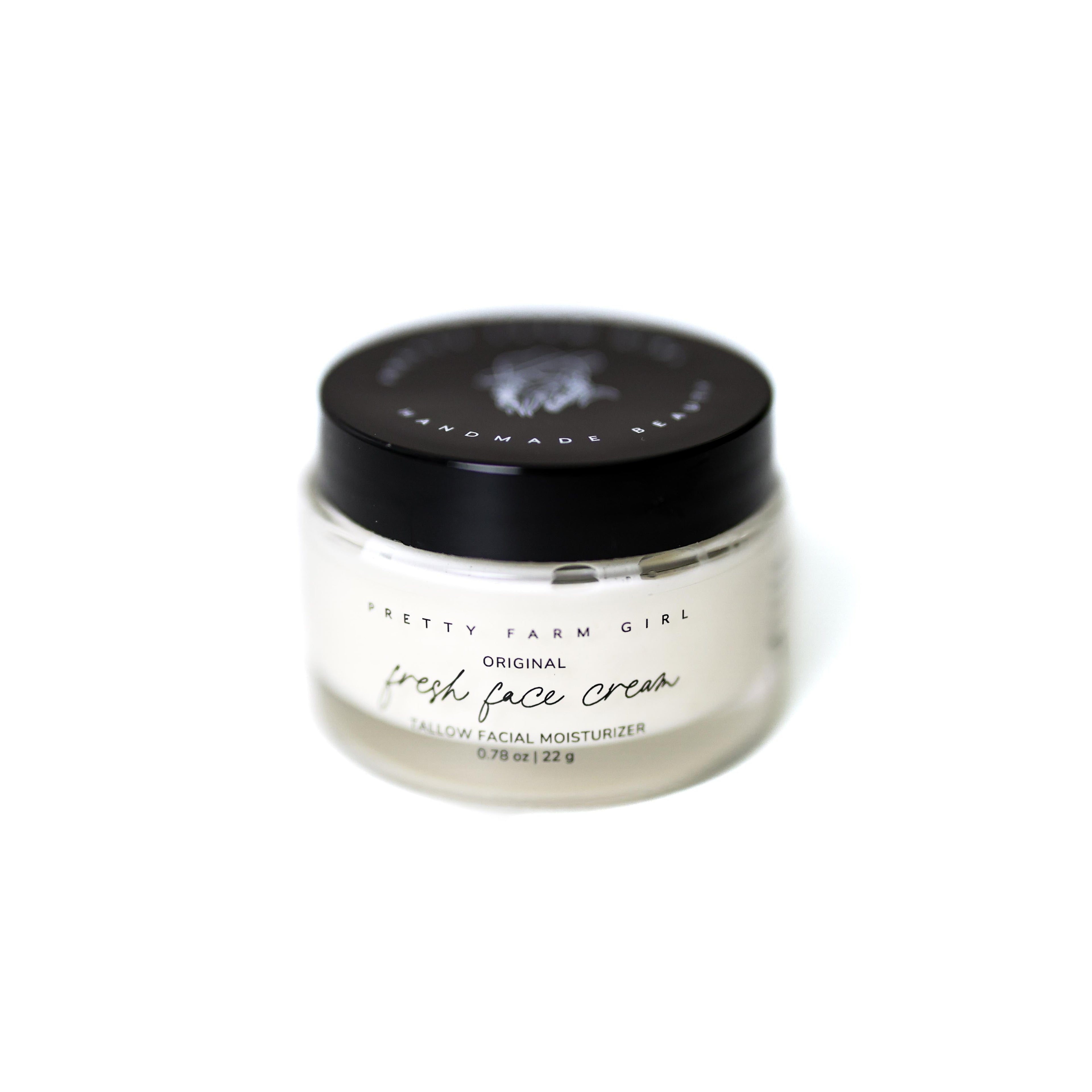 Small glass jar of tallow anti-aging face moisturizer with black lid on a clean surface