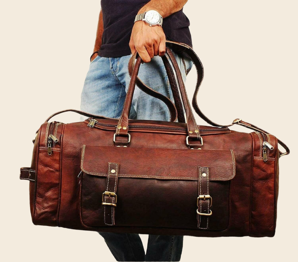 Vintage brown full-grain goat leather weekender duffle bag with brass hardware and matching toiletry bag on neutral background