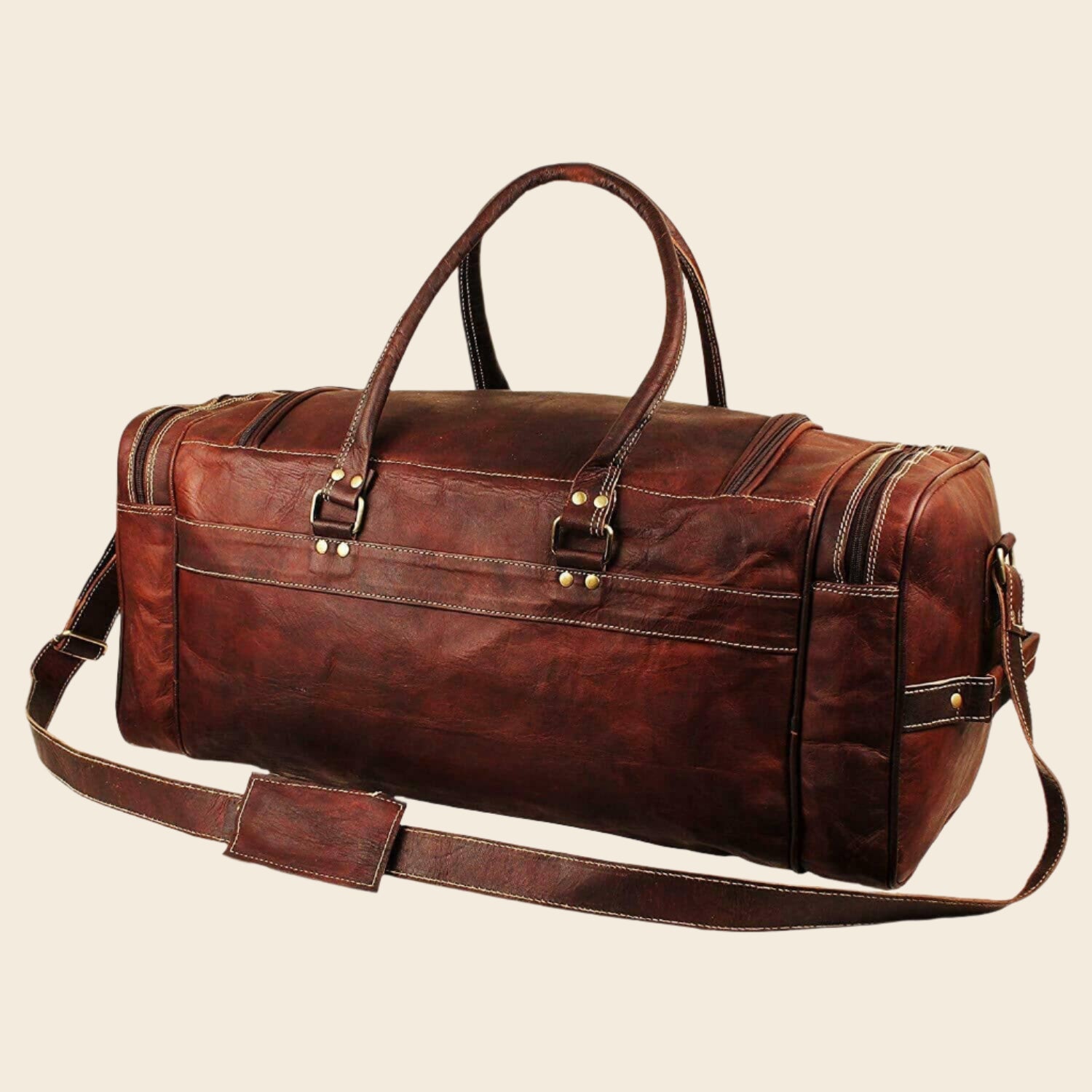 Vintage brown full-grain goat leather weekender duffle bag with brass hardware and matching toiletry bag on neutral background