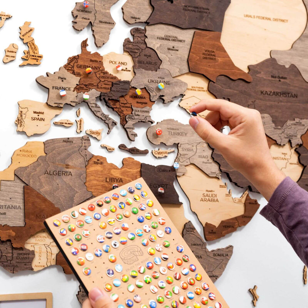 Multicolor 3D layered wooden world map wall art with engraved country names and borders mounted on a neutral wall