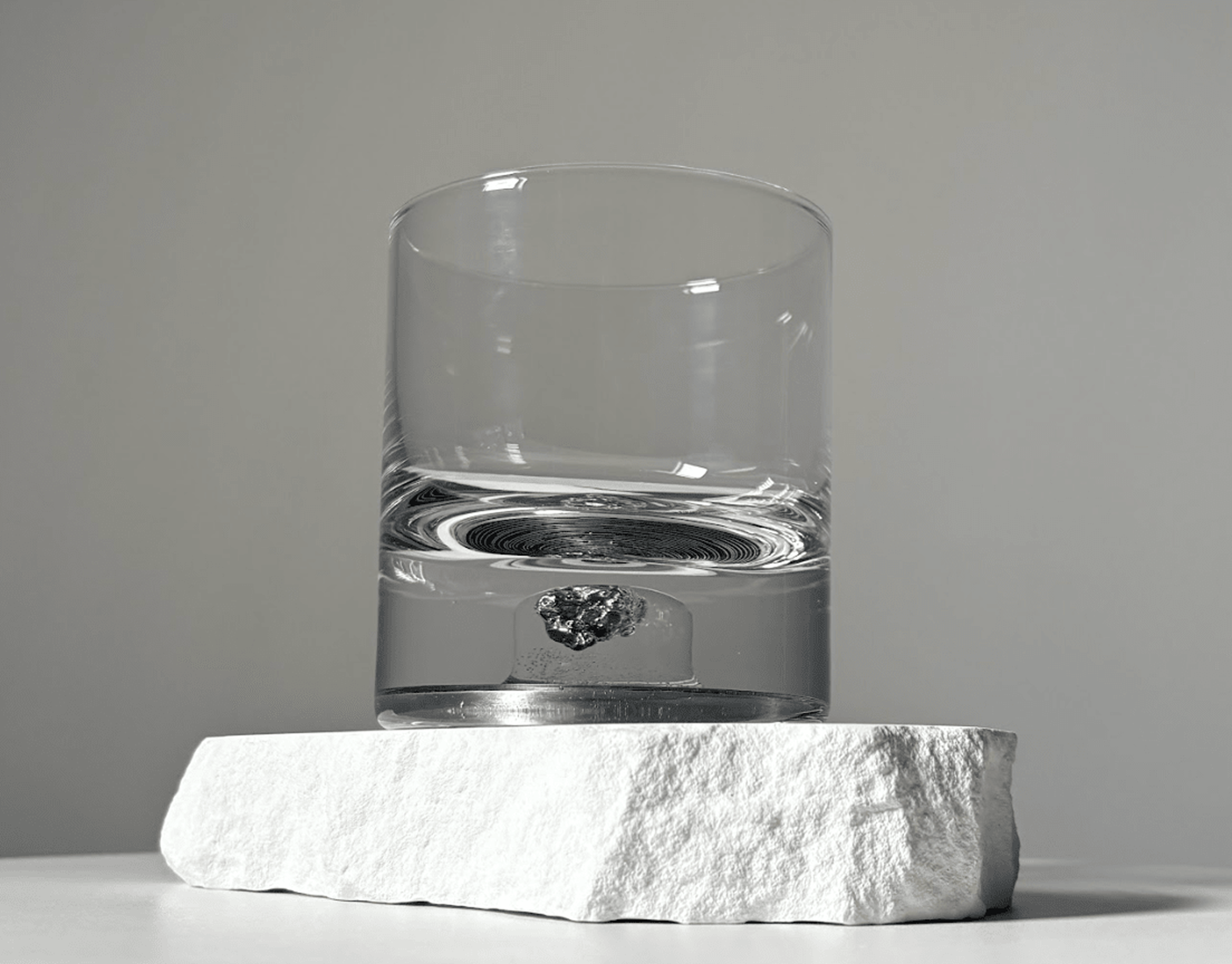 Set of two glass tumblers with genuine meteorite fragments suspended in high-clarity bases, shown in Antique Tin and Amber Gold finishes