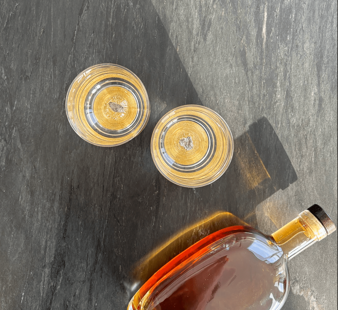 Set of two glass tumblers with genuine meteorite fragments suspended in high-clarity bases, shown in Antique Tin and Amber Gold finishes