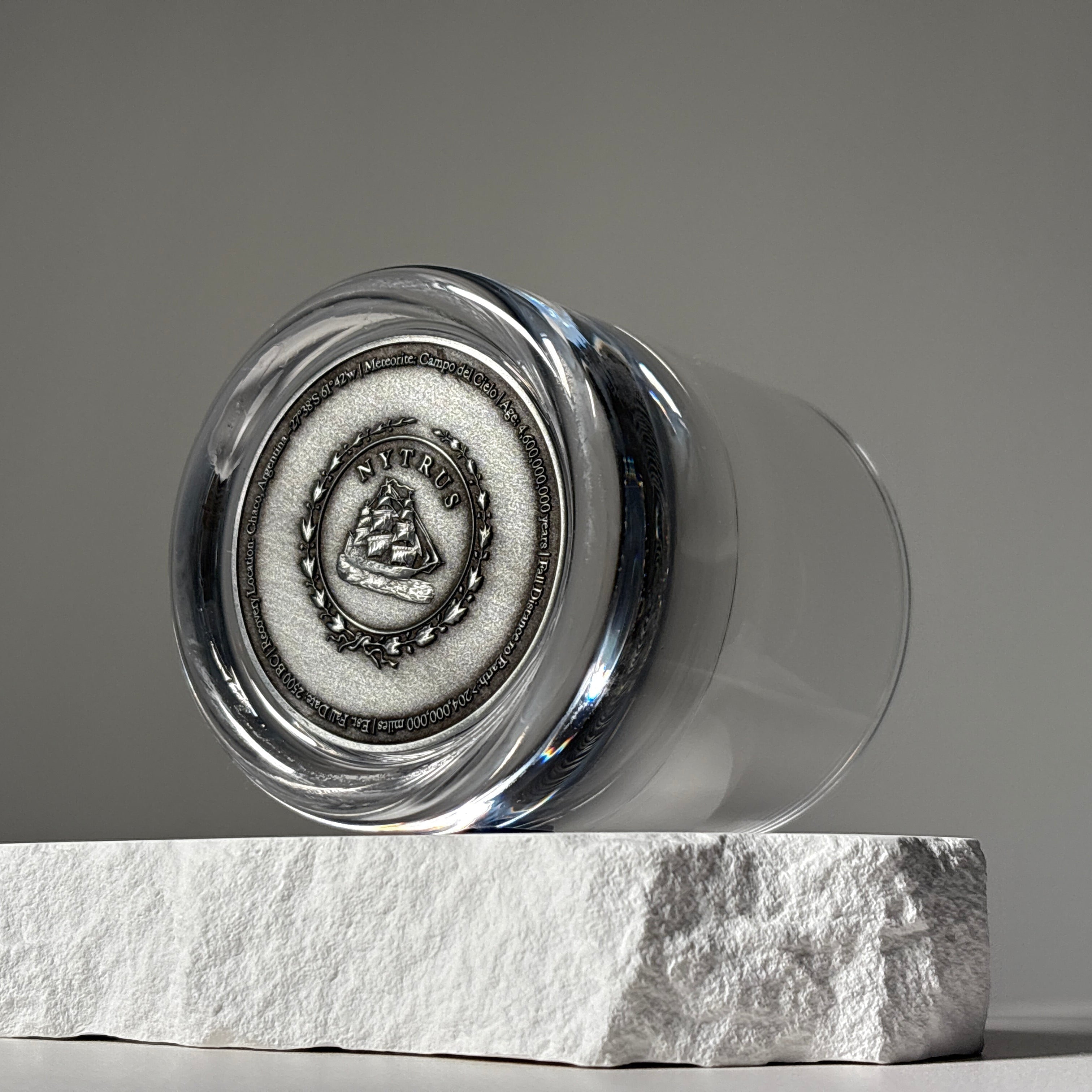 Set of two glass tumblers with genuine meteorite fragments suspended in high-clarity bases, shown in Antique Tin and Amber Gold finishes
