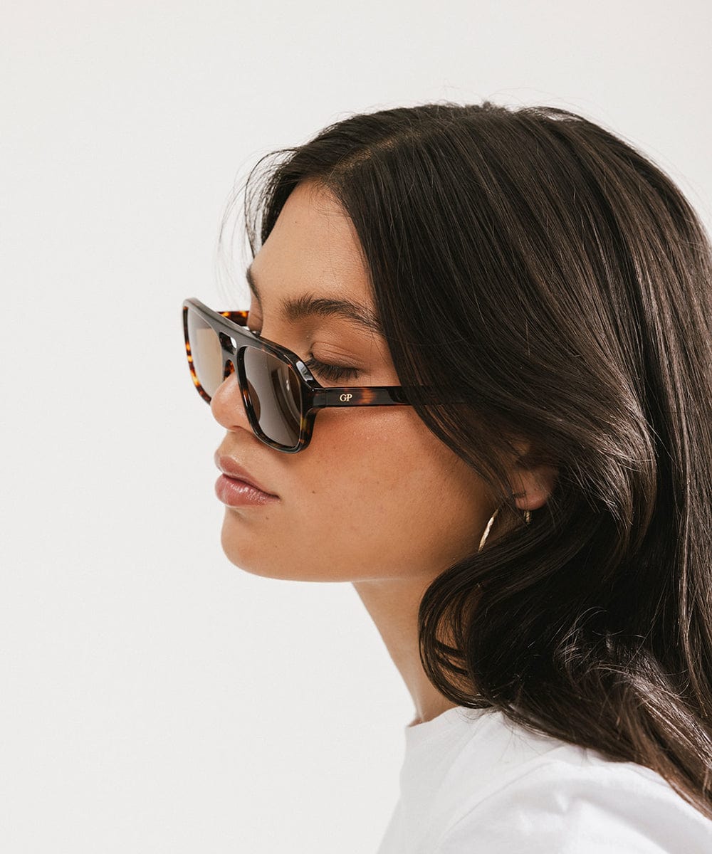 Men's rectangular vintage-inspired aviator sunglasses with light lenses and a gold-tone frame, shown with leather storage case
