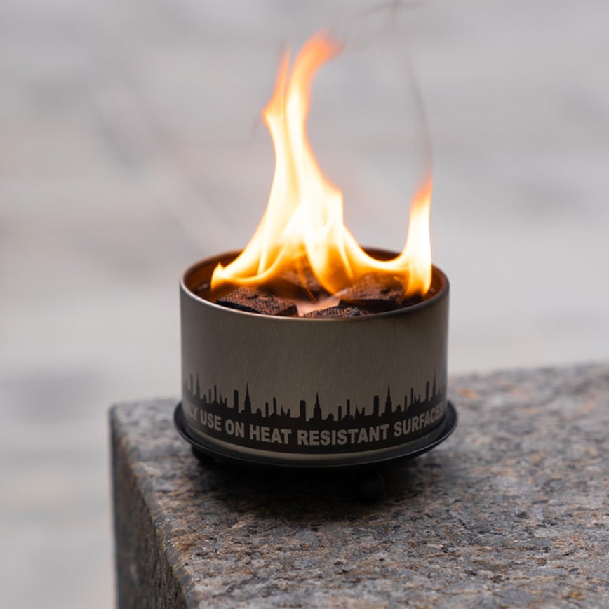 Matte black wrought iron trivet and candle holder with three ball feet on a neutral surface
