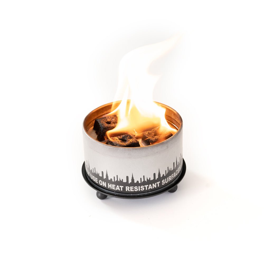 Matte black wrought iron trivet and candle holder with three ball feet on a neutral surface