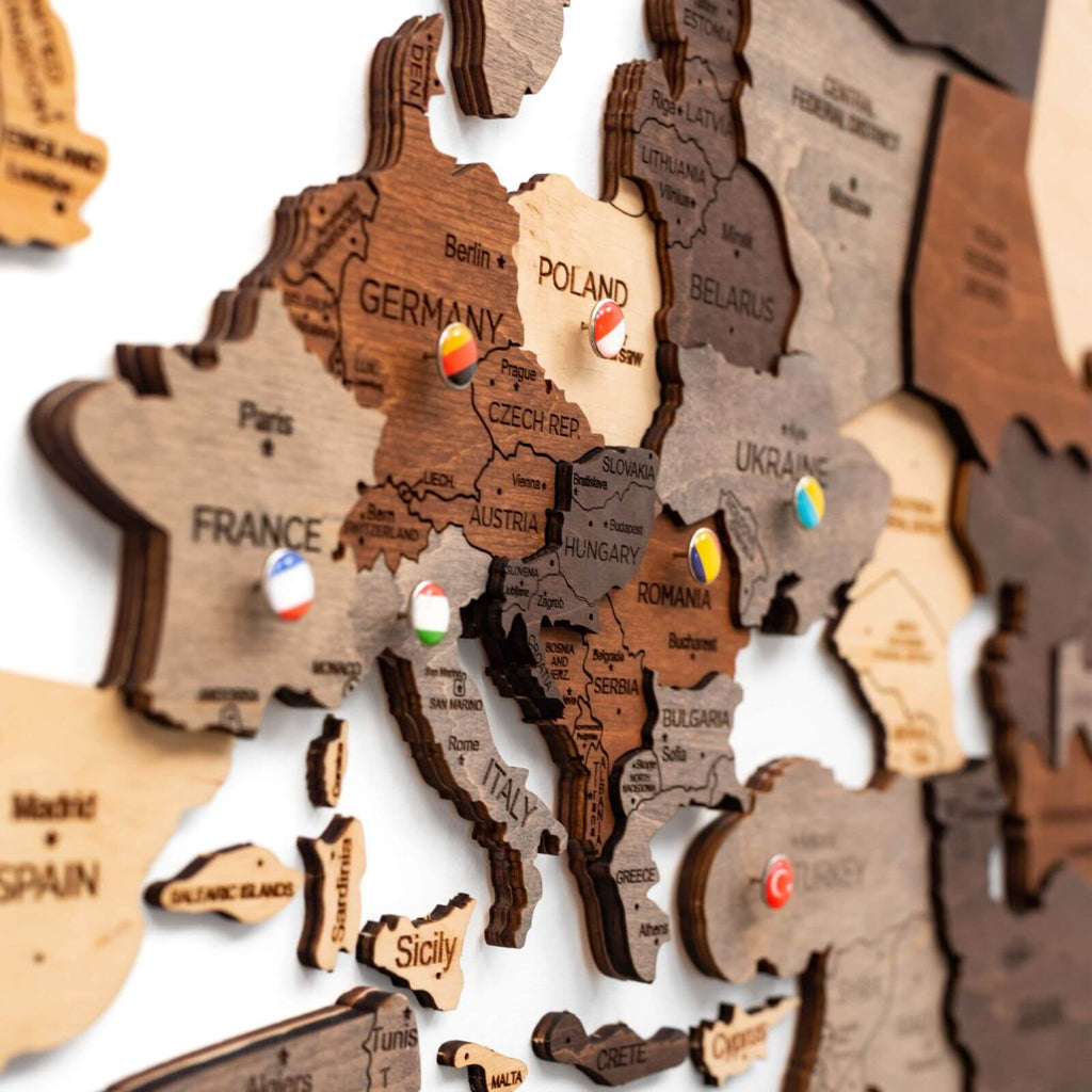 Multicolor 3D layered wooden world map wall art with engraved country names and borders mounted on a neutral wall